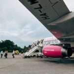 Pasażerowie schodzący po schodach z samolotu linii Wizz Air na lotnisku.
