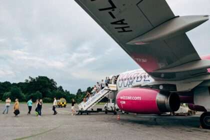 Pasażerowie schodzący po schodach z samolotu linii Wizz Air na lotnisku.