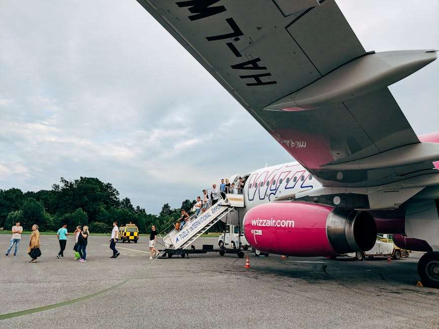 Pasażerowie schodzący po schodach z samolotu linii Wizz Air na lotnisku.
