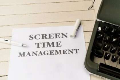 Biała kartka z napisem „SCREEN TIME MANAGEMENT” leży obok fragmentu starej maszyny do pisania.