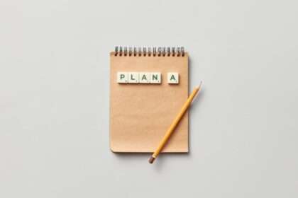 notatnik z ołówkiem i kostkami scrabble ułożonymi w napis "PLAN A"